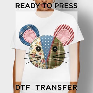 May include: White t-shirt featuring a mouse face design. The mouse face is made of patchwork fabric in various patterns and colors, including blue plaid, floral, and red stripes. The text "READY TO PRESS" and "DTF TRANSFER" are at the top and bottom.