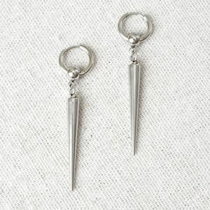 Pode incluir: Um conjunto de três canecas de cerâmica com acabamento fosco e salpicado. As canecas são em tons de creme, cinza claro e cinza escuro. Cada caneca tem um design simples e minimalista.