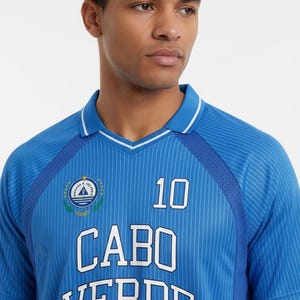 May include: A blue short-sleeved jersey with a white pinstripe pattern, a collar with white trim, and dark blue mesh side panels. The front features the text CABO VERDE in white block letters, the number 10, and a circular emblem with a star and triangle.