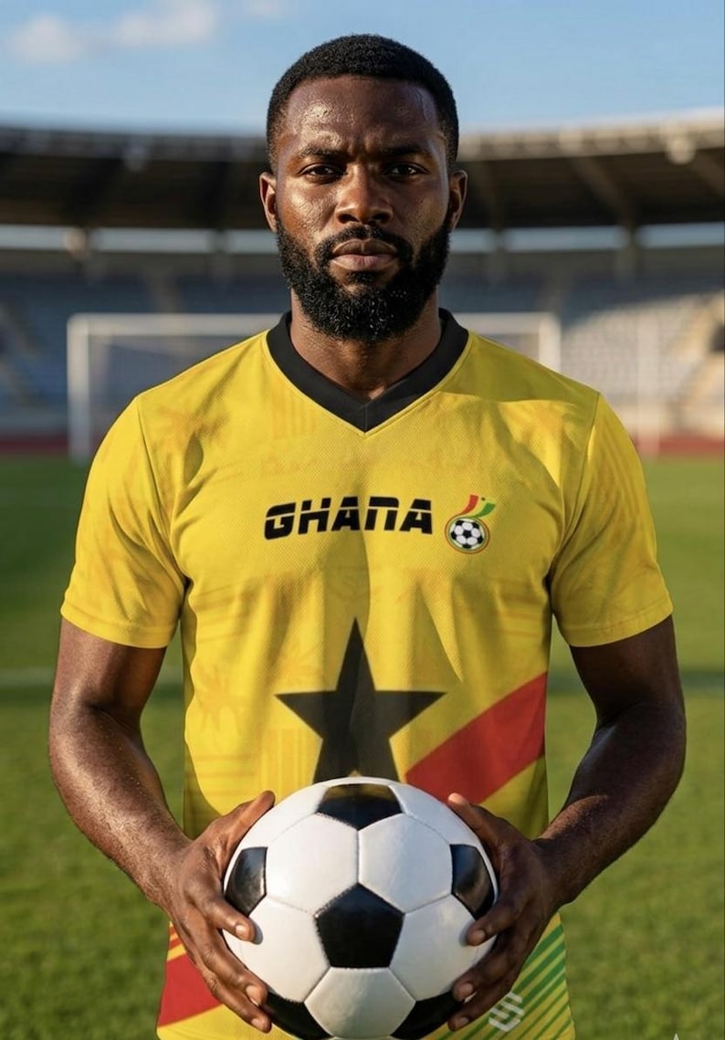 Pu&ograve; includere: Una persona indossa una maglia da calcio gialla del Ghana con una stella nera e la scritta "GHANA". La persona tiene in mano un pallone da calcio bianco e nero. Lo sfondo &egrave; un campo verde e una porta.