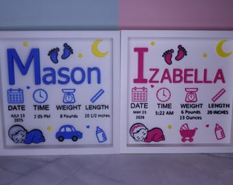 Könnte beinhalten: Zwei quadratische weiße Rahmen mit Geburtsdaten. Das linke Schild zeigt den Namen Mason in Blau mit Geburtsdatum 13. Juli 2025, Uhrzeit 14:05 Uhr, Gewicht 8 Pfund und Länge 20,5 Zoll. Das rechte Schild zeigt den Namen Izabella in Pink.