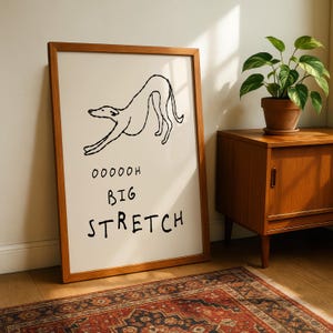 a framed drawing of a dog in a playful pose, accompanied by the text "OOOOH BIG STRETCH" in a humorous and exaggerated manner.