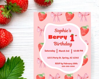 May include: A pink birthday invitation with a strawberry theme. The invitation reads "Sophie's Berry 1st Birthday" with the date, time, and location. Fresh strawberries and green leaves are scattered around the invitation on a white wooden surface.