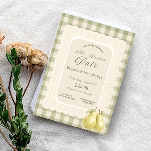 Könnte beinhalten: Ein Stapel Brautparty-Einladungen mit einem grün-weißen Vichy-Muster. Die Einladungen tragen den Text "The Perfect Pair" und Veranstaltungsdetails. Getrocknete Blumen und Grünzeug sind im Hintergrund.