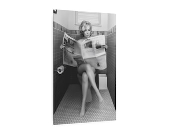 Könnte beinhalten: Schwarz-Weiß-Fotografie einer Person, die auf einer Toilette sitzt und eine Zeitung liest. Das Badezimmer hat eine geflieste Wand und einen gefliesten Boden. Eine Rolle Toilettenpapier befindet sich an der Wand. Die Person trägt dunkle Kleidung.
