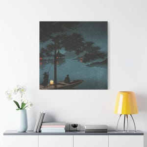 May include: A canvas print of a serene Japanese landscape at night. A boat with two figures floats on the water, illuminated by a lantern. Red lights dot the distant shore, under a dark sky and silhouetted trees.