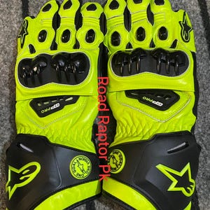 May include: A pair of neon yellow and black motorcycle gloves. The gloves have black protective panels on the knuckles and wrist. The gloves have the text "GP PRO" and a star logo.