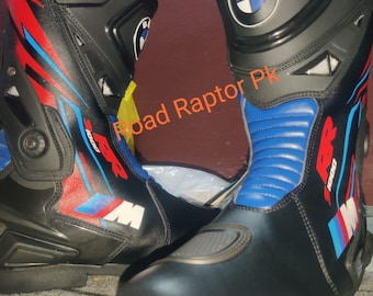 Puede incluir: Par de botas de moto negras con detalles en azul, rojo y blanco. Las botas presentan el logotipo de BMW y el texto "1000". Las botas tienen un diseño protector y están hechas de un material duradero.