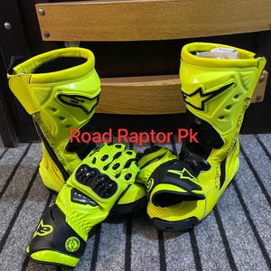 May include: Bright yellow and black motorcycle boots and gloves. The boots have a high-top design with black accents and the brand logo. The gloves are also yellow and black, featuring protective padding. The text "Road Raptor Pk" is visible.