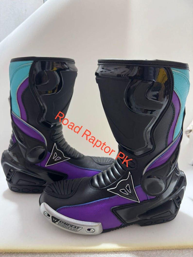 Może przedstawiać: Para czarnych i fioletowych but&oacute;w motocyklowych z turkusowymi i fioletowymi akcentami. Buty mają elegancki design z logo marki z boku i napisem "Road Raptor PK". Buty mają ochronny design.