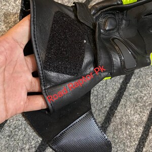 May include: Black motorcycle gloves with neon yellow accents. The gloves feature a hook and loop closure and a textured palm for grip. The gloves have a padded design for protection and are made of leather.
