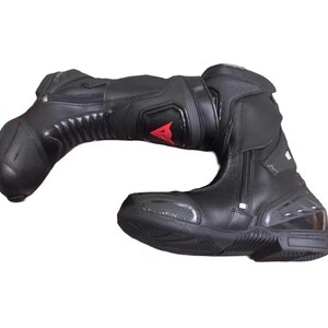 May include: Black motorcycle boot with a red logo. The boot features a zipper closure, reinforced panels, and a textured sole. The boot is designed for protection and performance.