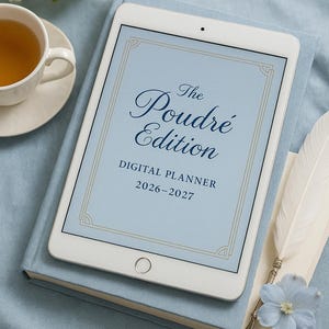 Puede incluir: Un planificador digital, "The Poudré Edition 2026-2027", en una tableta, descansa sobre un libro azul. Una taza de té y flores están en el fondo. También hay una pluma y una flor azul.