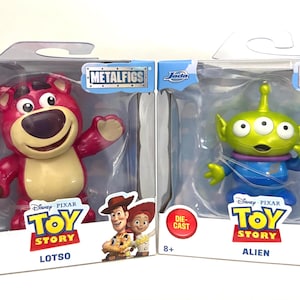 May include: Two die-cast metal figures from the Disney Pixar Toy Story franchise. One is Lotso, a pink bear with a cane. The other is an Alien, a green three-eyed character in a blue suit. Both are in their original packaging.