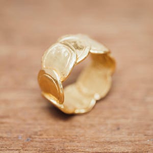 May include: A gold ring with a unique design featuring multiple overlapping circles. The ring is made of a smooth, shiny metal.