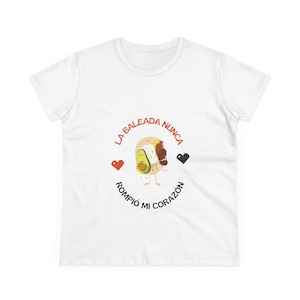 May include: White t-shirt featuring a cartoon design of a baleada, an avocado, and a heart. The text reads "La Baleada Nunca Rompió Mi Corazón" in red and black. The shirt is made of a soft, comfortable material.