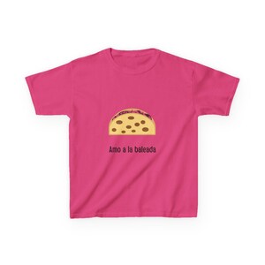 May include: A pink t-shirt featuring a cartoon baleada graphic. The baleada is a Honduran flour tortilla filled with beans, cheese, and other ingredients. The text "Amo a la baleada" is printed below the graphic.