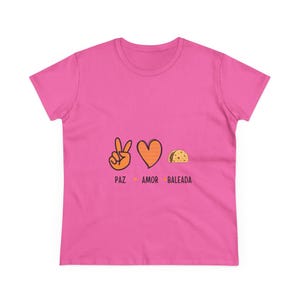 May include: A pink t-shirt featuring the words "PAZ AMOR BALEADA" below a peace sign, a heart, and a taco illustration. The peace sign is orange, the heart is orange with stripes, and the taco is yellow.