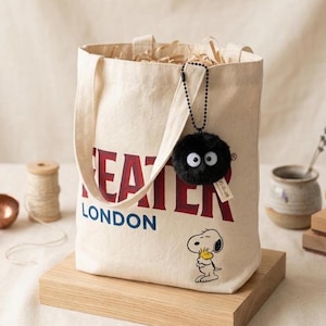 Black soot sprite keychain with a silver ball chain, styled next to a ceramic dish and dried lavender to emphasize the kawaii aesthetic and gift-ready presentation