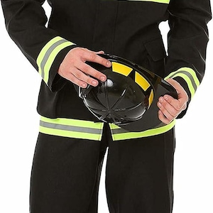 May include: A black firefighter costume featuring a jacket and pants with bright yellow reflective stripes. The jacket includes a red and gold fire department emblem on the chest. A black plastic helmet with yellow accents is held in the hands.