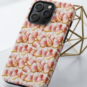 May include: A smartphone case featuring a repeating pattern of candy corn pieces. The design displays the iconic triangular shape of the candy with horizontal bands of white, orange, and yellow. The case has a cutout for a triple-lens camera system.