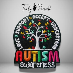May include: A circular black embroidered patch featuring a white tree with colorful puzzle piece leaves. The text LOVE SUPPORT ACCEPT UNDERSTAND circles the tree. The word AUTISM is in large colorful letters with awareness below.