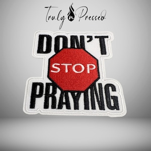 May include: Embroidered patch with the words "DON'T STOP PRAYING" in black block letters on a white background. A red stop sign is in the center. The patch has a white border and the words "Truly Pressed" in script at the top.