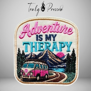 May include: A square embroidered patch with rounded corners featuring a pink camper van on a road, dark green pine trees, blue mountains, and a pink sun. The text reads Adventure IS MY THERAPY in pink, dark blue, and light blue thread.