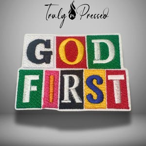 May include: Embroidered patch with the words "GOD FIRST" in colorful block letters. The patch features a white border and the text "Truly & Pressed" in cursive script at the top.