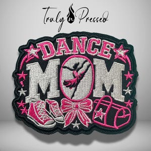May include: An embroidered patch featuring the text DANCE MOM in pink and silver thread on a black background. The design includes a silhouette of a dancer, a pink bow, a pair of pink sneakers, a pink duffel bag, and stars. The text Truly n Pressed is above.
