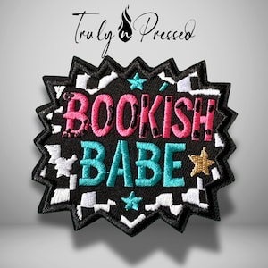 May include: Embroidered patch with the words "BOOKISH BABE" in pink and teal, surrounded by a black zig-zag border with white accents. A gold star and teal stars are also included. The patch has the text "Truly Pressed" at the top.