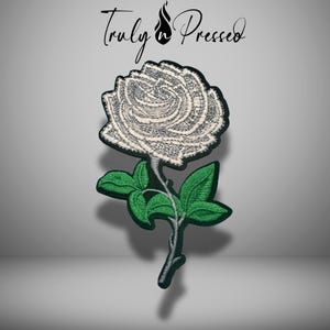 May include: Embroidered white rose patch with green leaves and stem. The patch has a black border and the text "Truly Pressed" in black script at the top. The rose is detailed with textured stitching.