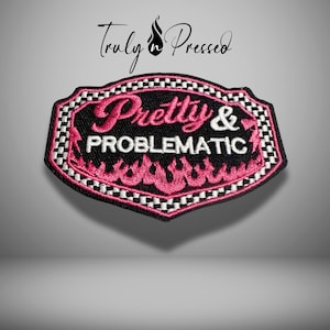 May include: Black and pink embroidered patch with the words "Pretty & Problematic". The patch has a black background with pink flames and a checkered border. The text "Truly n Pressed" is above the patch.