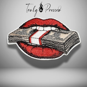 May include: Embroidered patch featuring a pair of red lips biting a stack of money. The patch has a white border and the text "Truly Pressed" above the lips. The money is secured with a red and white band.