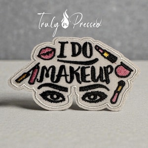 May include: Embroidered patch with the text "I DO MAKEUP" in black, featuring lipstick, mascara, and eye makeup illustrations. The patch is light gray with a white border and the words "Truly n Pressed" in script.