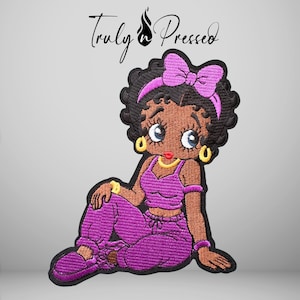 May include: An embroidered patch featuring a cartoon character with black hair, a purple headband with a bow, and gold hoop earrings. The character wears a purple crop top and matching sweatpants, with the text Truly Pressed above the figure.