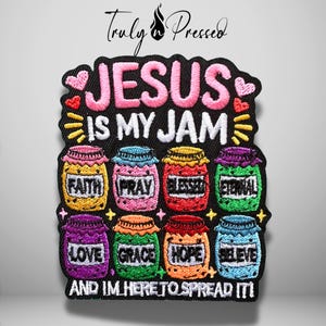 May include: A black embroidered patch featuring the text "JESUS IS MY JAM" in pink and white, surrounded by small hearts and stars. Below, eight colorful jars are labeled with the words "FAITH," "PRAY," "BLESSED," "ETERNAL," "LOVE," "GRACE," "HOPE," and "BELIEVE."
