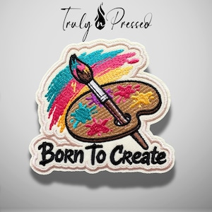 May include: An embroidered patch featuring a brown artist palette with colorful paint splatters, a paintbrush, and a vibrant rainbow-colored brushstroke. The text "Truly Pressed" appears above, and the text "BORN TO CREATE" is stitched in black below.