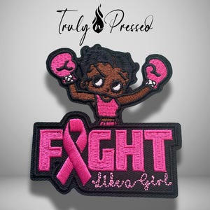 May include: An embroidered patch featuring a cartoon character wearing pink boxing gloves and a pink top. Below the character, the word FIGHT is stitched in pink with a pink awareness ribbon replacing the letter I, followed by the text like a girl.