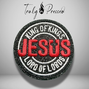 May include: A circular embroidered patch featuring a black glitter background with a white border. The word JESUS is stitched in bold red letters across the center. The text KING OF KINGS and LORD OF LORDS is embroidered in white along the border.