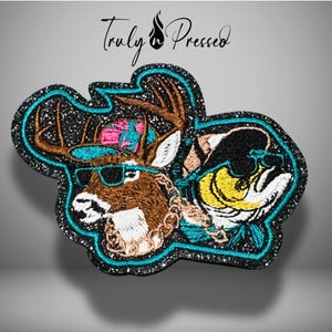 May include: An embroidered patch featuring a brown deer with antlers wearing a pink and teal patterned cap and sunglasses, next to a yellow fish wearing a black cap and sunglasses, both with gold chains, on a black glittery background with Truly Pressed text.