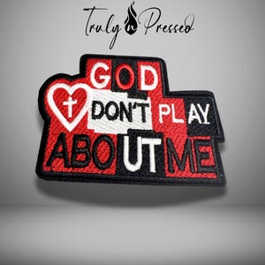 May include: Embroidered patch with the text "GOD DON'T PLAY ABOUT ME" in white and red. The patch features a heart with a cross and a black border. The patch is a religious statement.