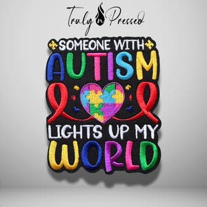 May include: A black embroidered patch featuring the text SOMEONE WITH AUTISM LIGHTS UP MY WORLD in colorful letters. The design includes a central heart filled with a multi-colored puzzle piece pattern and two red awareness ribbons on the sides.