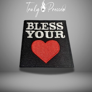 May include: Black square patch with the words "BLESS YOUR" in white block letters above a red heart. The patch is embroidered with a black border. The brand name "Truly n Pressed" is in the top left corner.