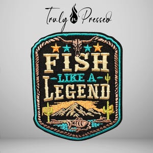May include: A rectangular embroidered patch with a black background featuring the text FISH LIKE A LEGEND in tan and teal. The design includes a steer skull, stars, cacti, a mountain range, and a fish, all framed by a rope-style border in teal.