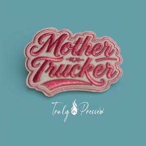 May include: A pink and white embroidered patch with the words "Mother Trucker" in a cursive font. The patch has a light pink border and is set against a teal background. The text "Truly n Pressed" is written in white script below the patch.
