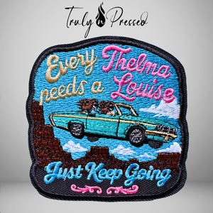 May include: An embroidered patch with a black border featuring a turquoise convertible car driving through a brown desert landscape. The text reads Every Thelma needs a Louise and Just Keep Going in gold, pink, and blue thread against a blue sky.