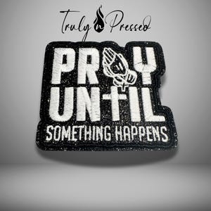 May include: Black and white embroidered patch with the words "PRAY UNTIL SOMETHING HAPPENS". The patch features a praying hands graphic and a glittery black border. The words are in a bold, blocky font.