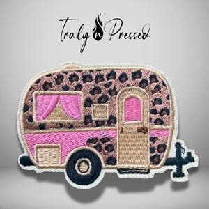May include: An embroidered patch shaped like a vintage camper trailer featuring a tan and brown leopard print pattern, bright pink curtains, a pink lower stripe, a tan door, and a black wheel. The text Truly n Pressed is printed above.