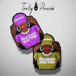 May include: Two embroidered patches featuring a person wearing a baseball cap with the word FEARLESS and a shirt with the text Black Queens MATTER. One patch is purple and the other is olive green, both showing silver hoop earrings and necklaces.